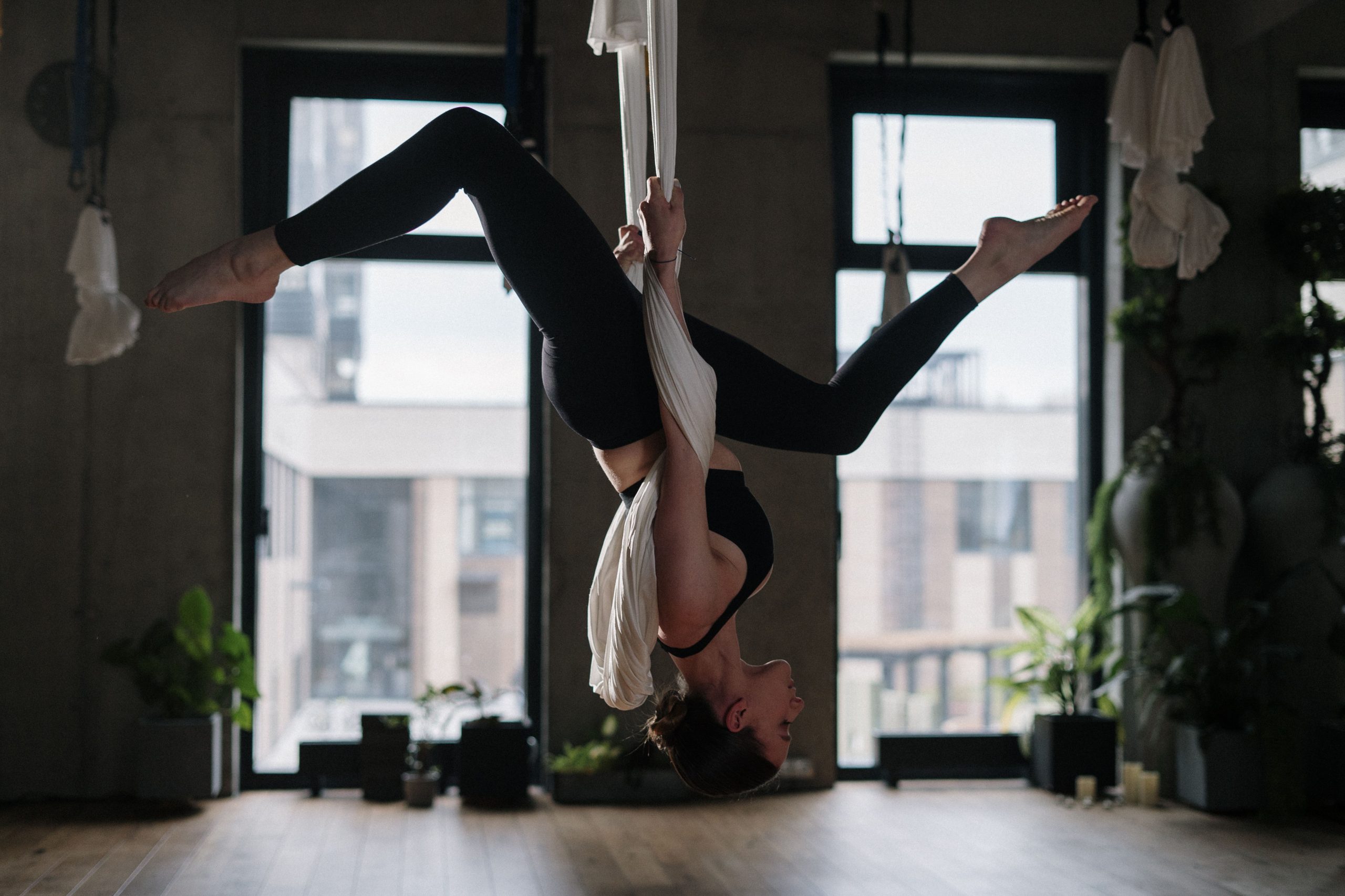 Practicată cu ajutorul unor materiale textile suspendate, această disciplină combină posturile clasice de yoga cu elemente din artele acrobatice. Foto: pexels.com